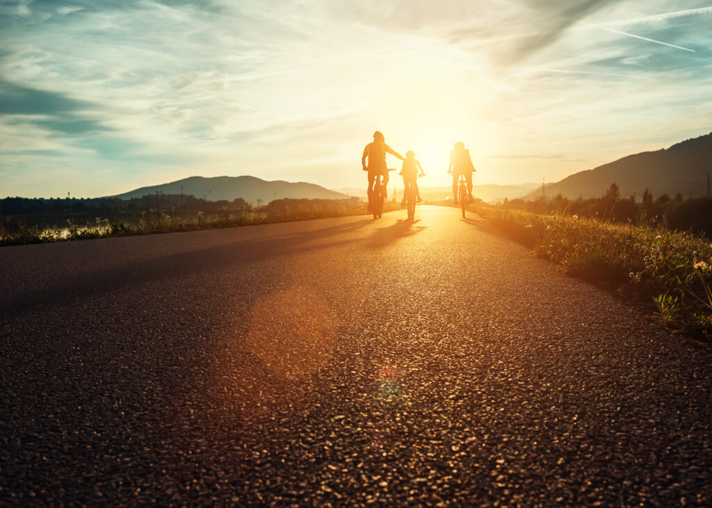 Family on their bicycles, riding towards the sunset - Symbolization of what the bible says about health and wealth.