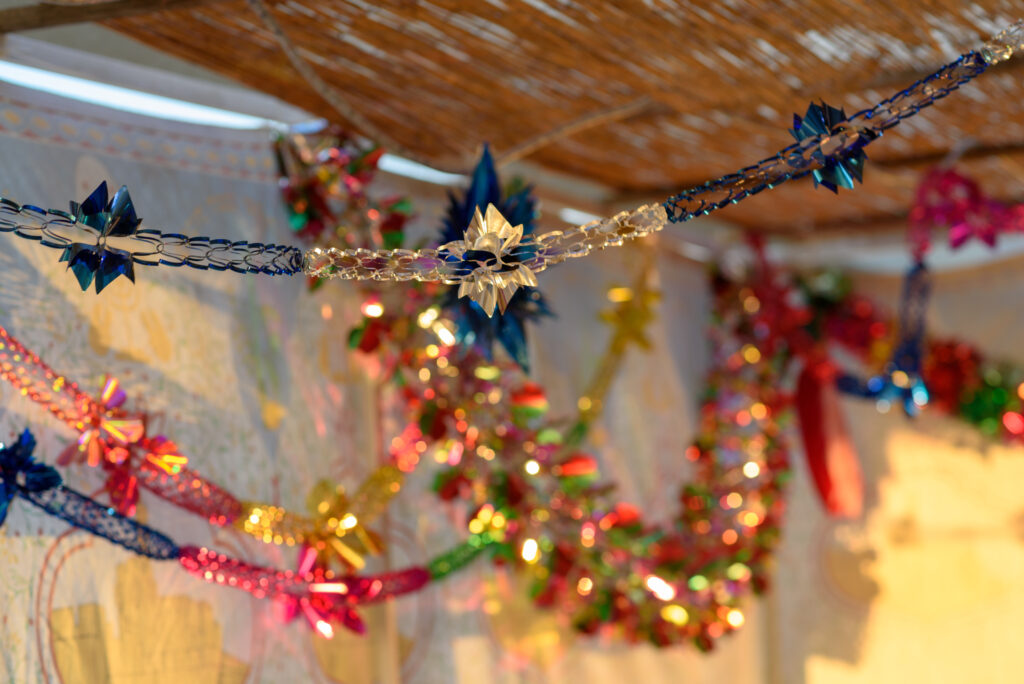 Colorful Sukkah decoration with shiny garland at sunset light.