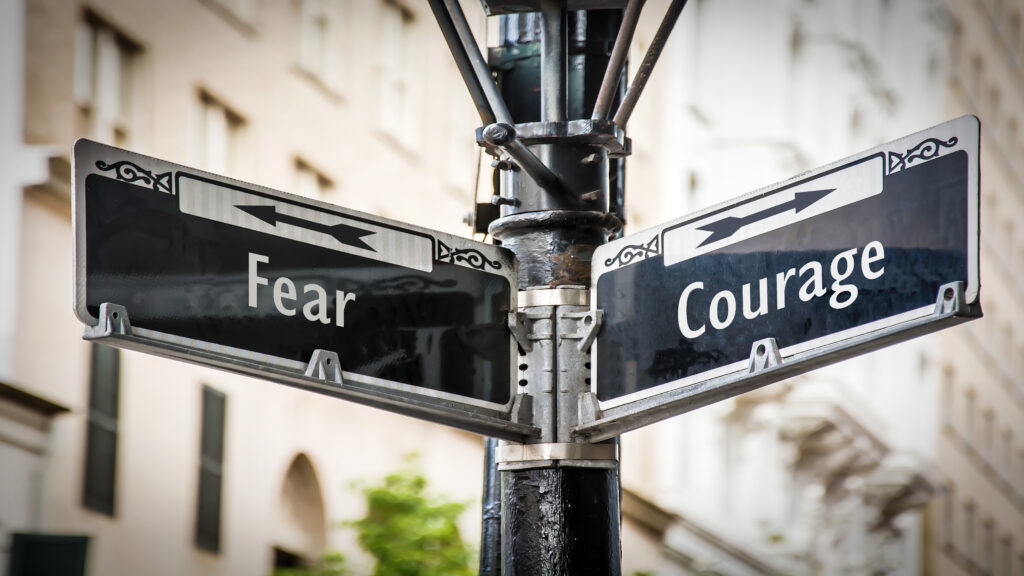 Street sign with fear and courage pointing in opposite directions.
