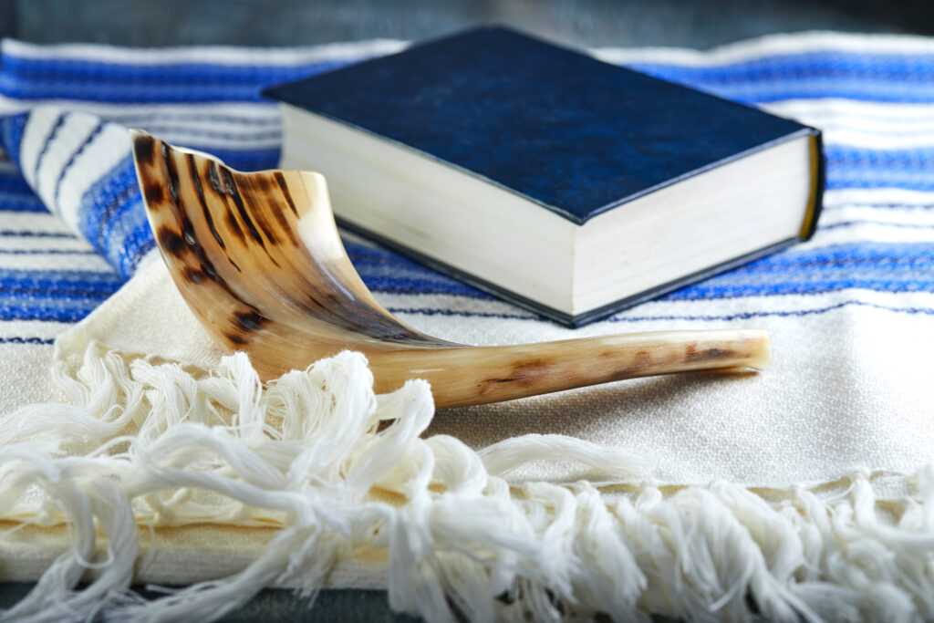 Bible with a shofar, resting on a tallit.