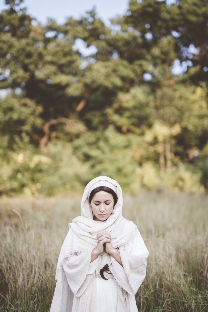Lone Woman Standing in a field, praying wearing biblical garments. 