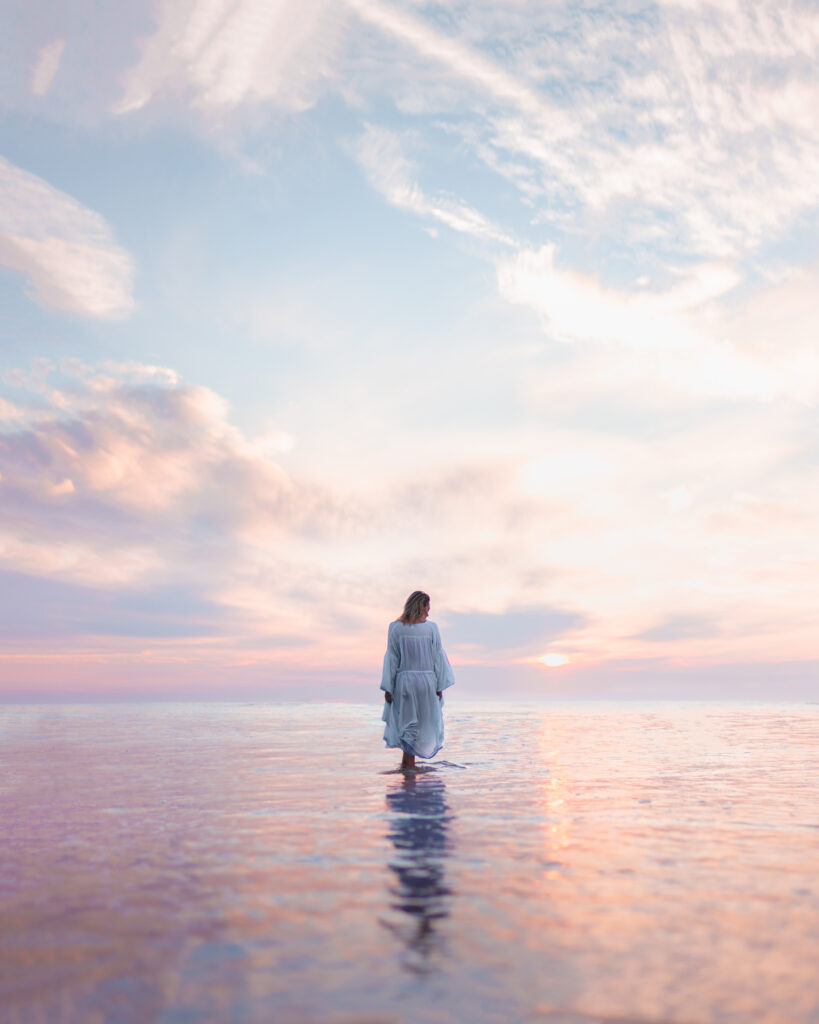 Woman in white dress walking on water during sunrise as representation of faith.