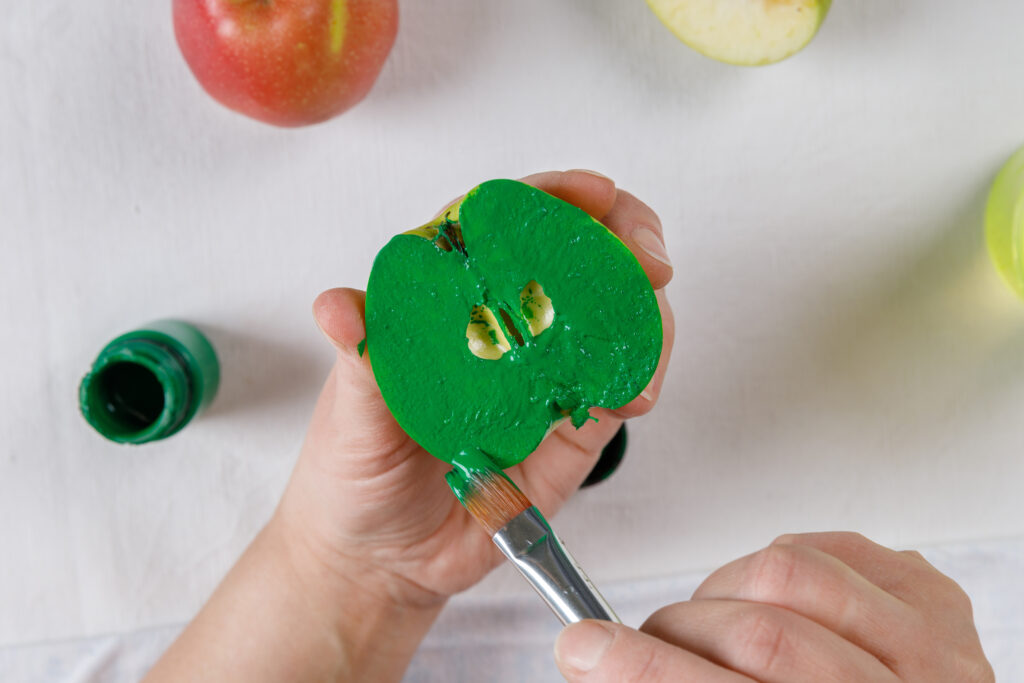 Person doing a craft and they are painting an apple. 