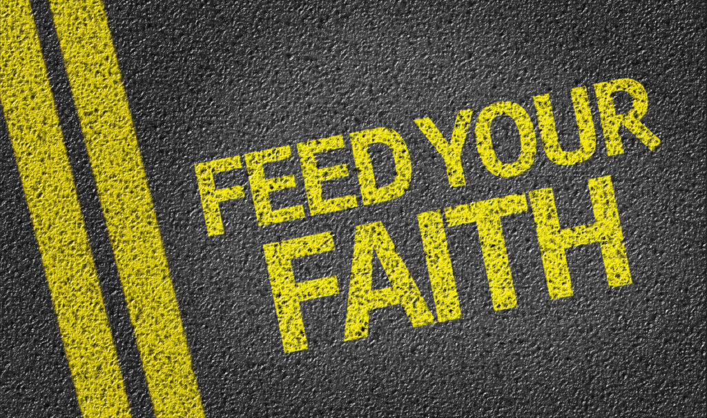 Feed your Faith written in yellow on road.
