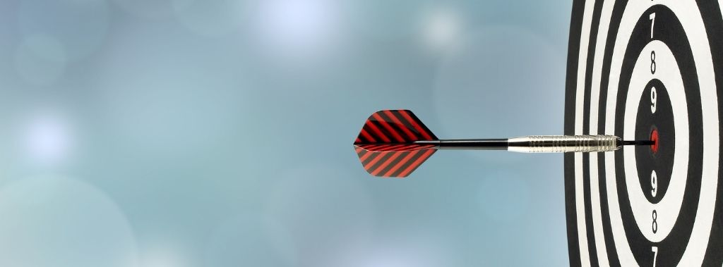 Close-up of red and black striped dart hitting center of target as concept for shifting gaze and staying focused on God.
