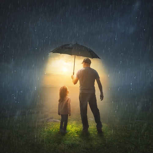 Father and daughter under an umbrella, revealing sunshine in rain; concept of God's covering.
