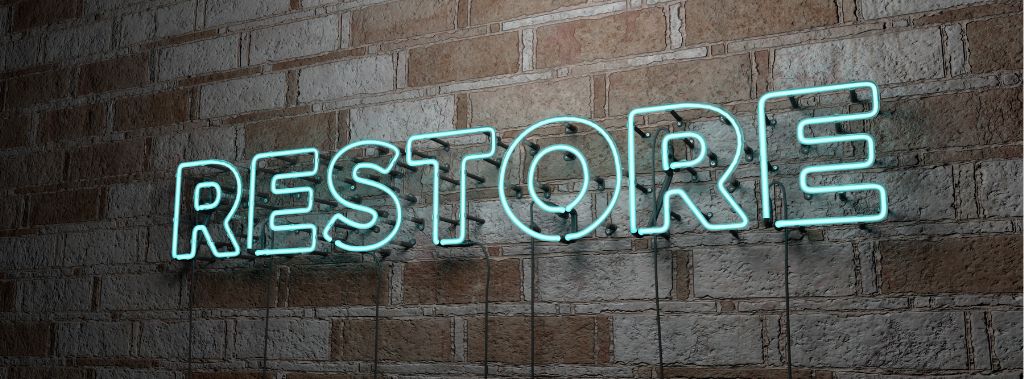 A neon sign that says "Restore" against a brick wall.