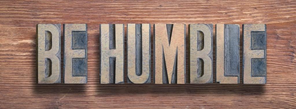 Weathered wooden blocks spelling out the words be humble.