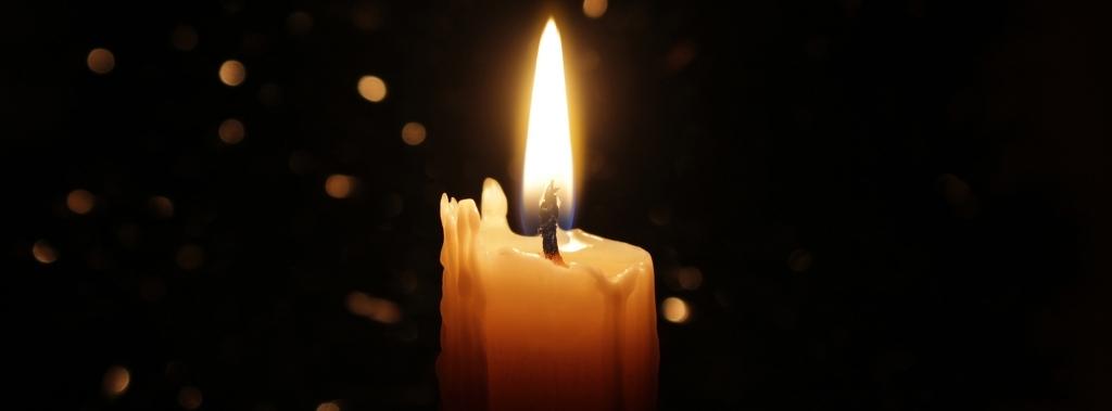 Burning white candle with black background.