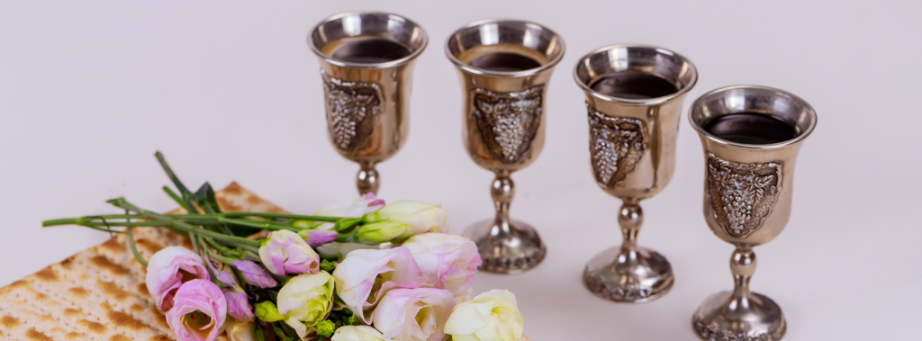 Four Passover cups, flowers, and matzah