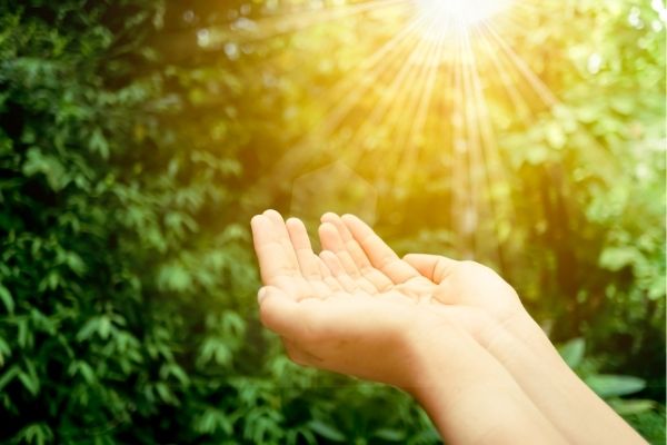 A woman cupping her hands to the sunlight. 