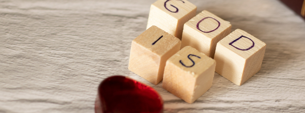 GOD IS written on wooden blocks and a red glass heart on a table to say that God is love.