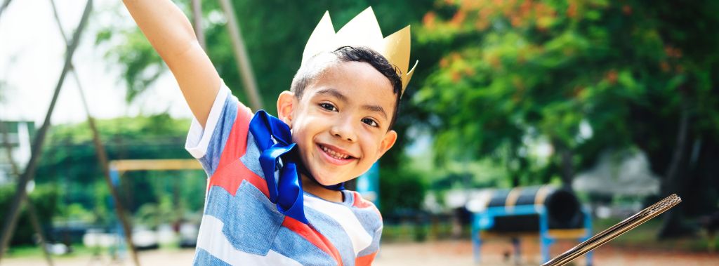 Happy kid outside wearing a crown on his head. 
