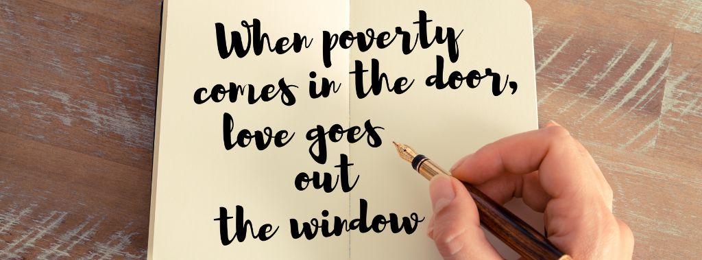  A hand holding a calligraphy pen and writing the words when poverty comes in the door, love goes out the window on notebook.