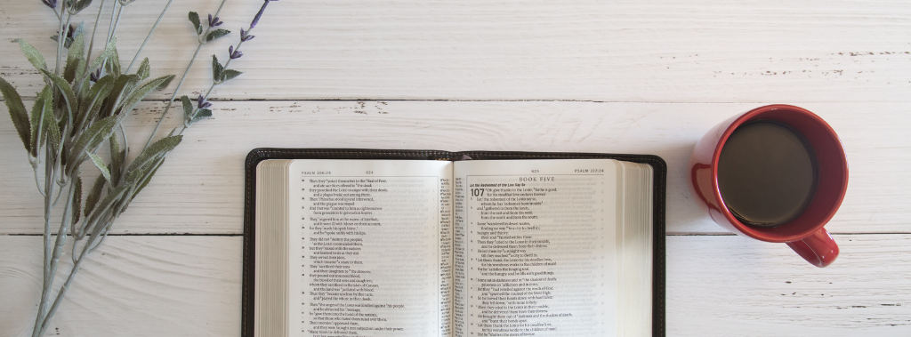bible open on white wooden table with cup of coffee