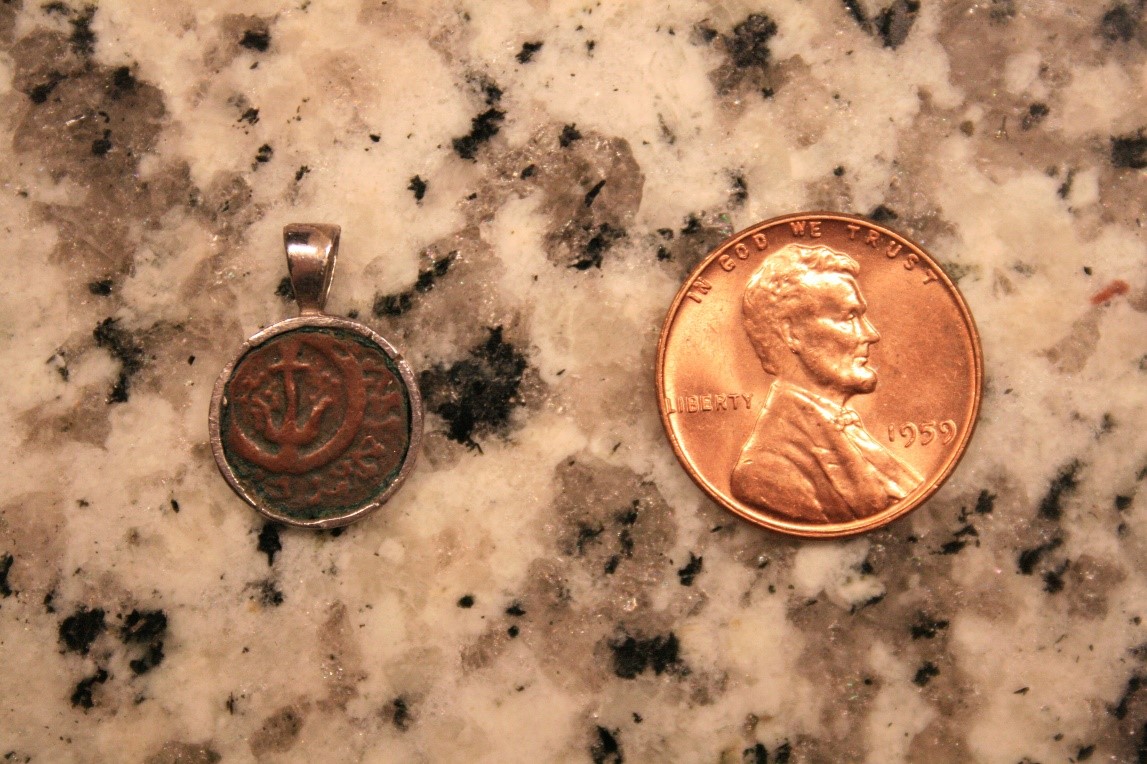 A back-facing “Widow’s Mite” or Lepton 103-76 B.C. on granite countertop next to a 1959 A.D. U.S.A. copper penny for scale.