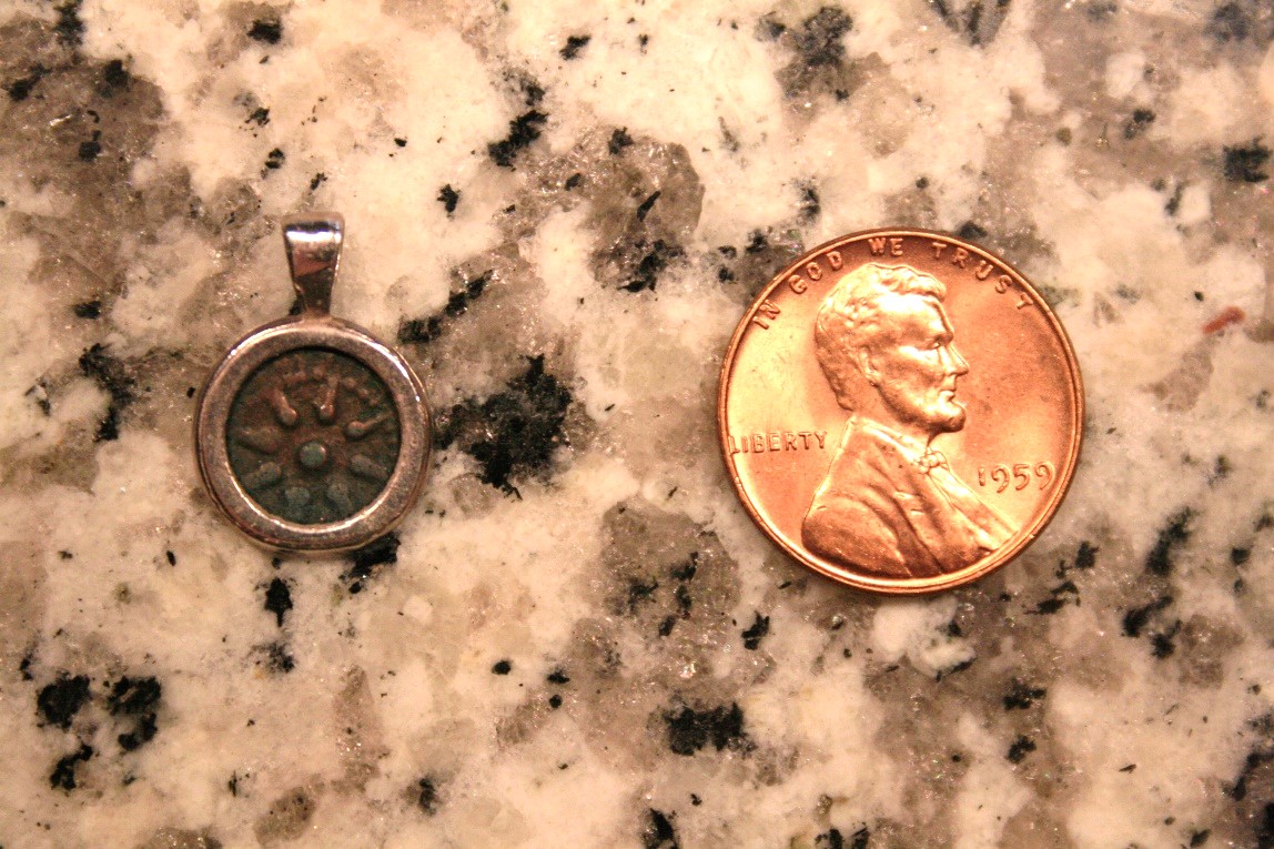 A front-facing “Widow’s Mite” or Lepton 103-76 B.C. on granite countertop next to a 1959 A.D. U.S.A. copper penny for scale.