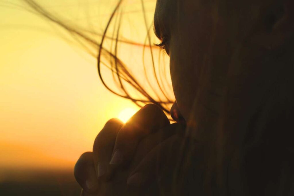 Close up of woman fervently praying with hands folded.
