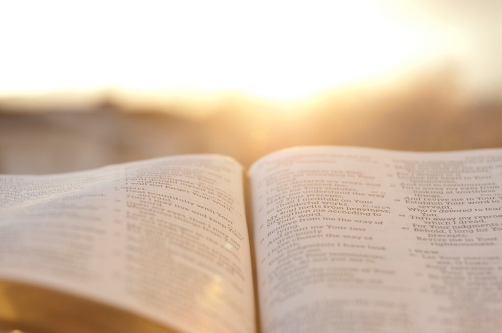 Close up of open Bible with bright sunset in the background.